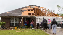 Tetangga dan keluarga membantu membersihkan rumah yang rusak di Monroe, La, (12/4/2020). Sedikitnya enam orang tewas akibat amukan tornado di negara bagian Mississippi pada Minggu (12/4) waktu setempat. (Nicolas Galindo/The News-Star via AP)