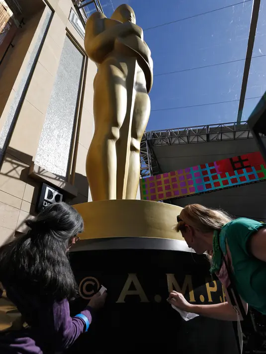 Seniman membersihkan tulisan patung Oscar di luar Teater Dolby saat persiapan jelang 88 Academy Awards di Hollywood, California (24/2). Piala Oscar merupakan penghargaan film Amerika untuk menghargai suatu karya industri film. (REUTERS/Mario Anzuoni)