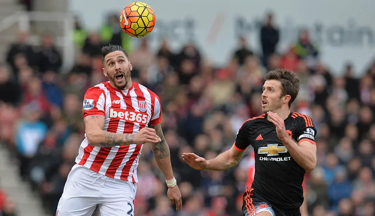 Bek Stoke, Geoff Cameron, duel udara dengan Kapten Manchester United, Michael Carrick, pada liga Premier League. (AFP/Paul Ellis)