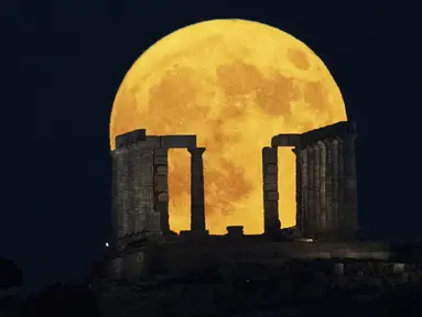 Bulan purnama terbesar atau supermoon muncul di belakang Kuil Poseidon di Tanjung Sounio, selatan Athena, Senin (19/8/2024). (AP Photo/Michael Varaklas)