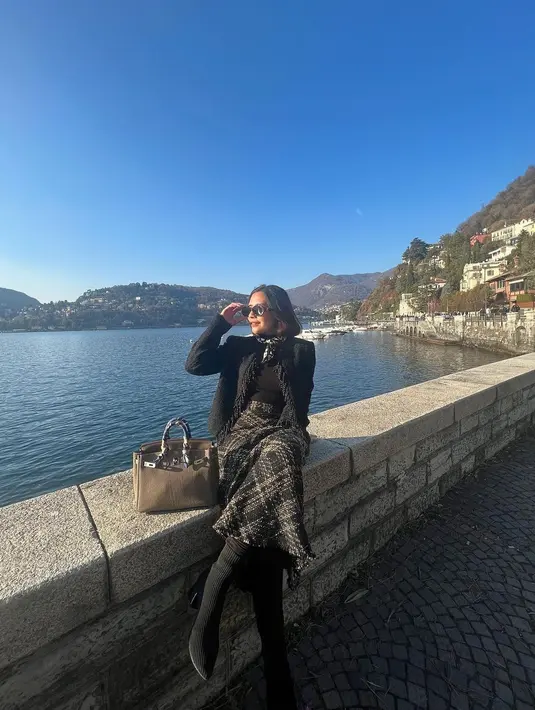 Blazer dengan aksen fringe di tepian itu dipadukan rok tweed panjang dan sepatu boots. [@prillylatuconsina96].