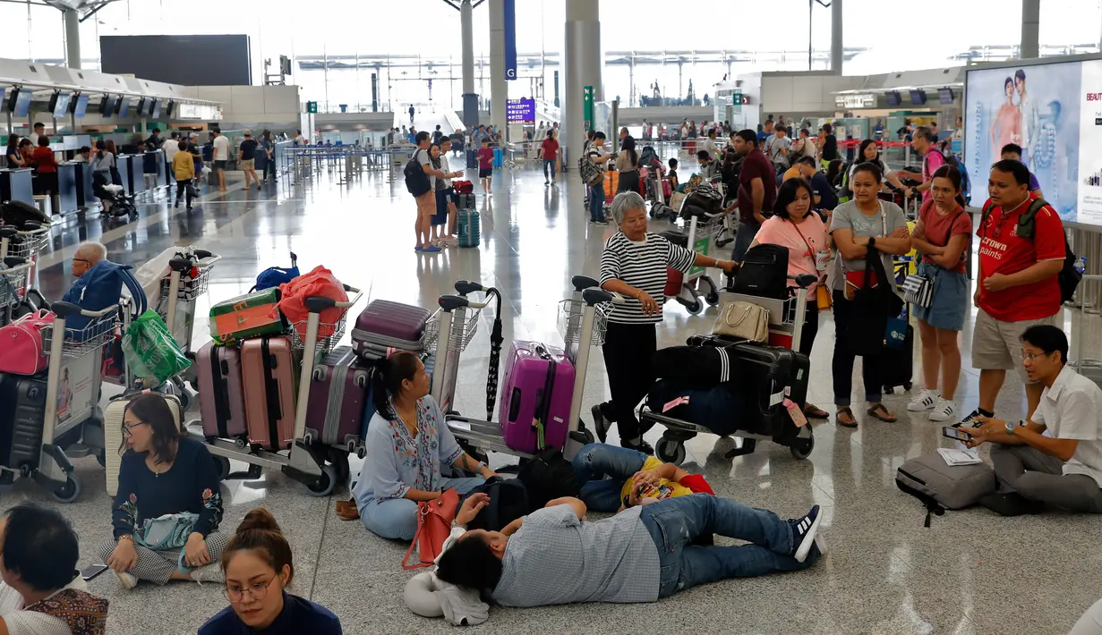 Calon penumpang menunggu jadwal keberangkatan pesawat di bandara Hong Kong, Rabu (14/8/2019). Bandara Hong Kong kembali membuka penerbangan keberangkatan pada Rabu pagi setelah sempat lumpuh selama dua hari akibat demonstran menduduki salah satu bandara tersibuk di dunia tersebut. (AP/Vincent Thian)