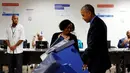 Pekerja membantu Presiden AS Barack Obama ketika akan memberikan suaranya di mesin voting elektronik di TPS awal di pusat kota Chicago, Jumat (7/10). Obama memberikan suaranya lebih awal untuk Pilpres AS pada 8 November 2016. (REUTERS/Jonathan Ernst)