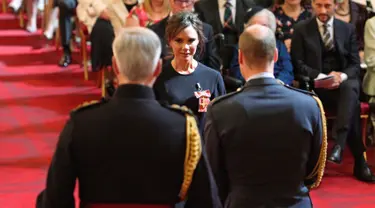 Desainer Victoria Beckham saat menerima gelar Order of the British Empire (OBE) dari Pangeran William di Istana Buckingham, London (19/4). Ibu 4 anak ini mendapatkan gelar kehormatan di bidang fashion selama 17 tahun.  (Yui Mok / PA via AP)