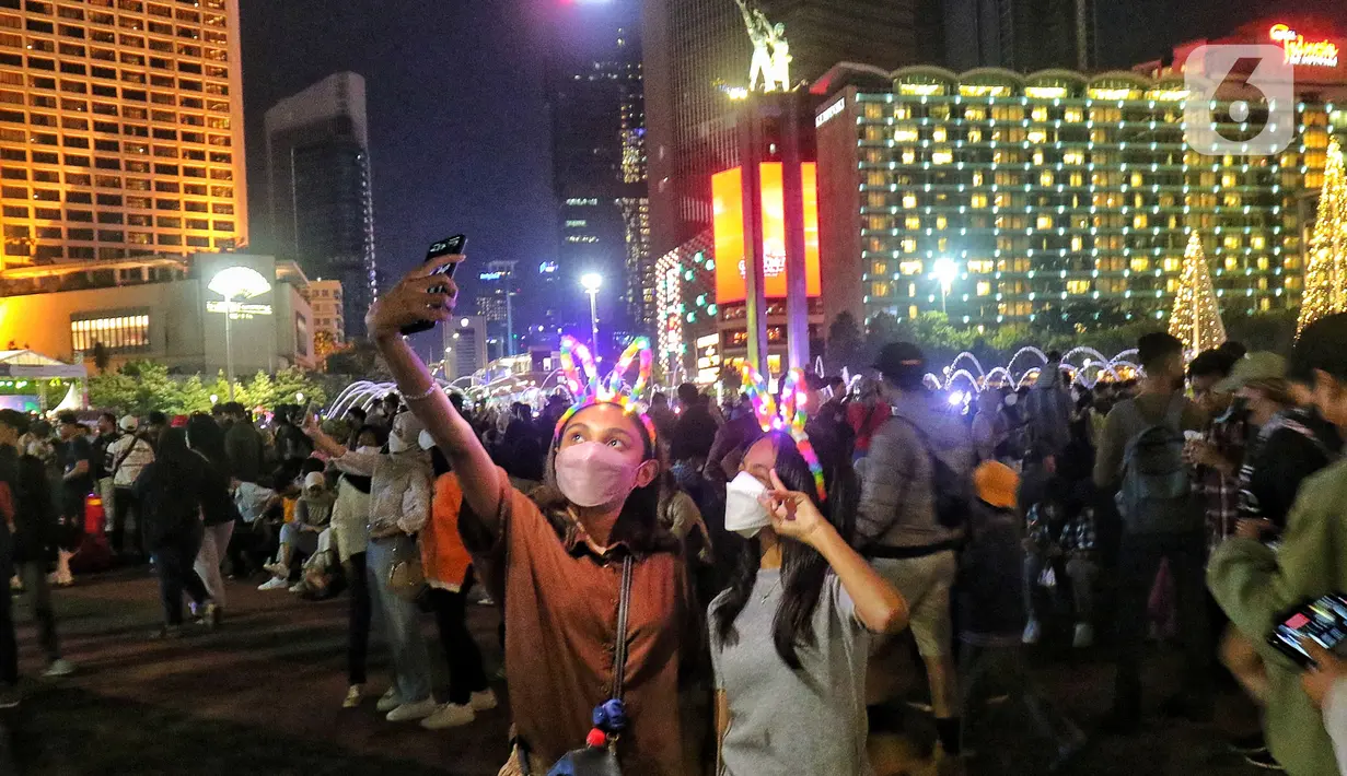 Warga memadati Car Free Night (CFN) pada malam pergantian tahun baru 2023 di kawasan Bundaran Hotel Indonesia, Jakarta, Sabtu (31/12/2022). Banyak warga yang berkumpul merayakan pergantian tahun baru sambil berswafoto, menikmati kuliner, berjalan hingga bersepeda santai. (Liputan6.com/Angga Yuniar)