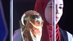 Seorang wanita melihat trofi Piala Dunia FIFA  saat tur Dunia di Ibu Kota Kairo, Mesir (15/3). ). Trofi ini terbuat dari emas murni 18 karat dengan dasar perunggu, setinggi 36,8 sentimeter dan berat 6,1 kilogram. (AFP Photo/Khaled Desouki)