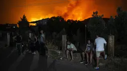 Sejumlah warga menunggu untuk dievakuasi dari desa Psachna selama kebakaran hutan di dekat desa Makrimalli di pulau Evia, timur laut Athena, Yunani (13/8/2019). Akibat kebakaran hutan ini perdana menteri Yunani membatalkan liburanya. (AFP Photo/Angelos Tzortzinis)