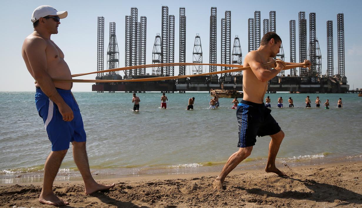 Anak-anak yang tergabung dalam sekolah kickboxing sedang berlatih di tepi Laut Kaspia dekat dengan bekas tempat pengeboran minyak era Soviet di kota Baku, Azerbaijan, Sabtu (27/6). (AP Photo/Dmitry Lovetsky)