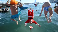 Para peserta tradisi lomba renang unik saat natal di pelabuhan tua Barcelona (Port Vell Barcelona), Spanyol, Senin (25/12/2023) waktu setempat. (AFP/Josep Lago)