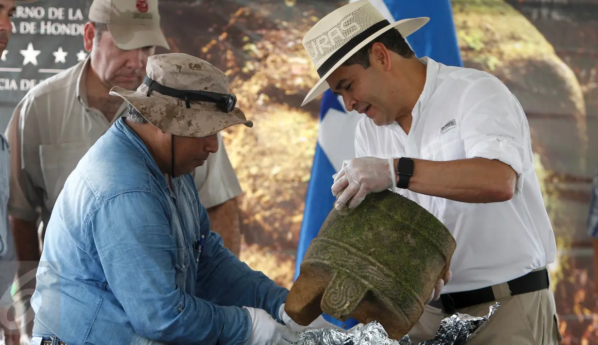 Presiden Honduras, Juan Orlando Hernandez (kanan) dan seorang arkeolog saat memamerkan benda kuno pada upacara di Catacamas, Honduras, (12/1). Benda - benda kuno ditemukan pada 2012 yang menyudut pada legenda "Kota Putih". (REUTERS / Jorge Cabrera