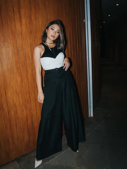 Atau kenakan crop top sebagai outerwear. Marion Jola terlihat mengenakan tank top hitam yang dipasangkannya dengan celana panjang berwarna serasi. Ia melapisi atasannya dengan crop top tanpa tali berwarna putih. Foto: Instagram.