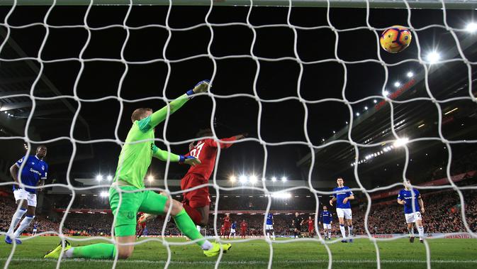 Penyerang Liverpool Divock Origi saat memasukan bola ke gawang kiper Everton, Jordan Pickford selama pertandingan Liga Inggris di Anfield Stadium (2/12). (AP Photo / Jon Super)