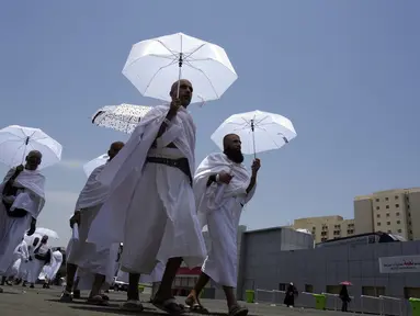 Jemaah haji berjalan sambil memegang payung di kamp tenda Mina, Makkah, Arab Saudi, Senin (26/6/2023). (AP Photo/Amr Nabil)