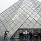 Turis berdiri di luar museum Louvre di Paris, Prancis pada Minggu (1/3/2020). Louvre, museum yang paling banyak dikunjungi di dunia, ditutup sementara untuk pengunjung setelah para staf menolak bekerja di tengah kekhawatiran terjangkit virus corona tipe baru, Covid-19. (AP/Rafael Yaghobzadeh)