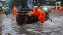 Petugas BPBD DKI Jakarta membantu pedagang mendorong gerobak melewati banjir yang merendam Jalan Kemang Raya, Jakarta Selatan, Kamis (4/1/2024) sore. (merdeka.com/Arie Basuki)