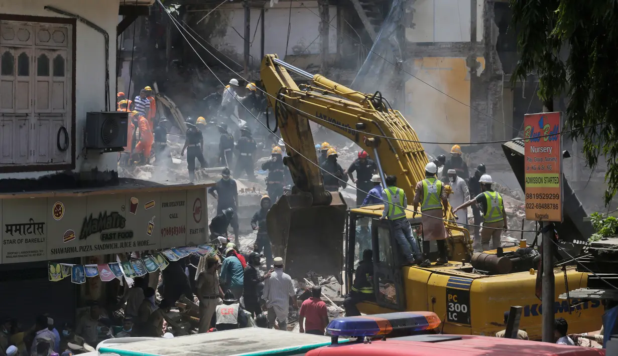 Petugas keamanan dan penyelamat menggunakan alat berat untuk mengevakuasi bangunan yag runtuh di Mumbai, India (31/8). Menurut pejabat setempat, sekitar 40 orang terjebak dalam reruntuhan bangunan tersebut. (AP Photo / Rafiq Maqbool)