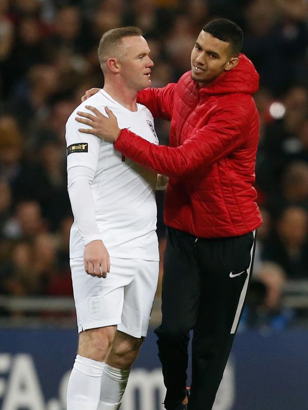 Seorang suporter menghampiri striker Inggris, Wayne Rooney selama pertandingan melawan Amerika Serikat (AS) di Stadion Wembley, Inggris (16/11). Rooney juga diberikan ban kapten dalam laga tersebut. (AFP Photo/Ian Kington)
