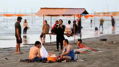 Warga Iran beristirahat sambil menikmati suasana di pantai di kota Laut Kaspia, Izadshahr, provinsi Mazandaran utara (8/7/2019). Laut Kaspia terletak di antara Eropa dan Asia, di sebelah barat dan barat-daya pegunungan Ural. (AFP Photo/Atta Kenare)