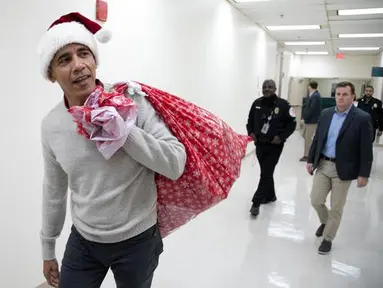 Mantan Presiden AS, Barack Obama mengunjungi Children's National Medical Center di Washington, Rabu (19/12). Dengan topi khas merah putih ala sinterklas, Obama membagikan hadiah natal untuk anak-anak yang sedang menjalani perawatan. (Chuck Kennedy / AFP)