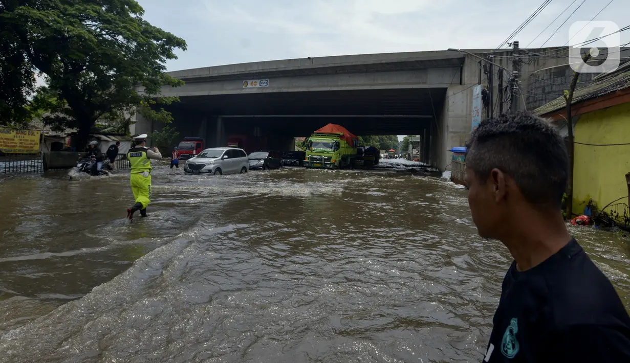 Petugas kepolisian mengatur lalu lintas saat banjir di Jalan Husein Nastranegara Perapatan Rawa Bokor, Tangerang, Sabtu (1/2/2020). Hujan deras yang mengguyur sejak Jumat (31/1) malam menyebabkan sejumlah kawasan di Tangerang terandam air. (merdeka.com/Imam Buhori)