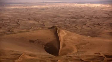 Pandangan dari udara sebuah bukit dikelilingi hamparan pasir Gurun Gobi wilayah Mongolia (21/7). Gurun terbesar di Asia ini sangat menakjubkan ketika dilihat dari udara. (AFP PHOTO / PATRICK BAZ)