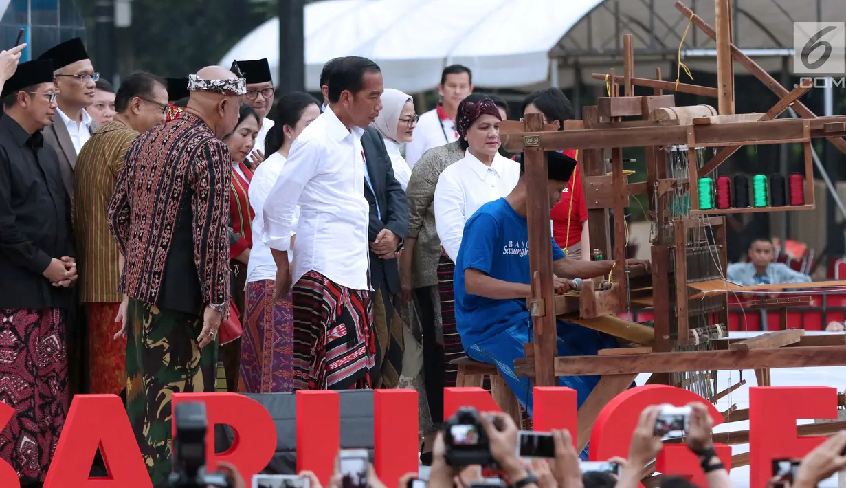 Presiden Joko Widodo melihat proses penenunan kain di Festival Sarung Indonesia 2019, Plaza Tenggara Kompleks GBK, Jakarta, Minggu (3/3). Festival ini untuk menghidupkan kesadaran generasi muda akan kekayaan budaya. (Liputan6.com/Helmi Fithriansyah)