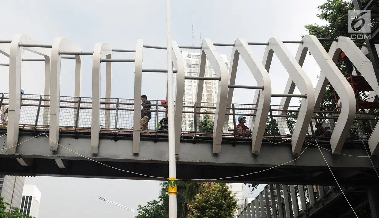 Petugas menyelesaikan proyek pembangunan jembatan penyeberangan orang (JPO) Gelora Bung Karno di kawasan Sudirman, Jakarta, Sabtu (5/1). Revitalisasi tiga di kawasan Sudirman ditargetkan selesai pada pertengahan Januari 2019 (Liputan6.com/Herman Zakharia)