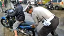 Polisi tengah membantu pengendara sepeda motor mogok karena genangan air yang masuk ke dalam mesin (Liputan6.com/Panji Diksana)