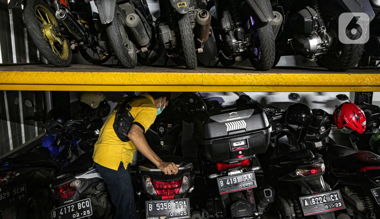 Pekerja mengatur sepeda motor yang diparkir di Soul Parking, Kebon Kacang, Jakarta, Jumat (21/1/2022). Tempat parkir vertikal tersebut bisa menyimpan lebih banyak motor di atas lahan sempit. (Liputan6.com/Faizal Fanani)