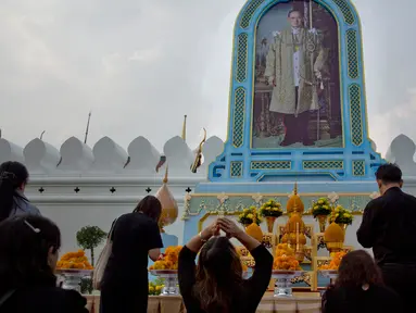 Warga Thailand memberi penghormatan di depan potret mendiang Raja Thailand Bhumibol Adulyadej di luar Grand Palace, Bangkok, Thailand (13/10). Upacara ini untuk memperingati satu tahun wafatnya Raja Bhumibol Adulyadej. (AP Photo/Gemunu Amarasinghe)