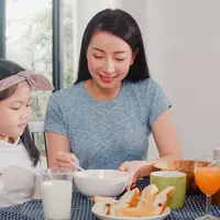 Seorang ibu yang sedang mengajarkan anaknya untuk makan sendiri (Foto dok : Freepik/tirachardz).