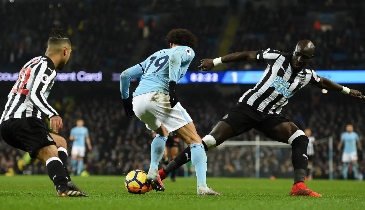 Gelandang Manchester City, Leroy Sane berebut bola dengan pemain Newcastle United, DeAndre Yedlin dan Mohamed Diame pada pertandingan pekan ke-24 Premier League di Etihad Stadium, Minggu (21/1). Manchester City meraih kemenangan 3-1. (Oli SCARFF/AFP)