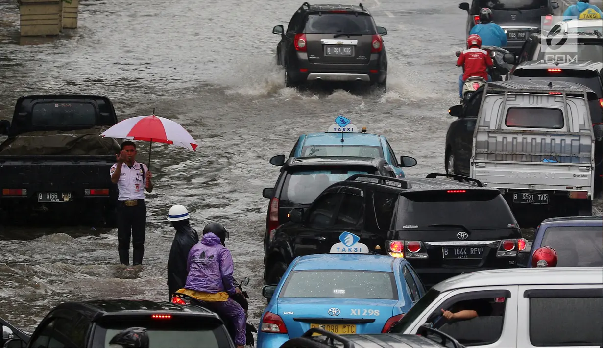 Petugas keamanan mengatur arus lalu lintas saat banjir merendam kawasan Gambir, Jakarta, Kamis (15/2). Banjir tersebut mengakibatkan jalan di sekitar lokasi terpaksa ditutup karena tidak bisa dilalui kendaraan bermotor.(Liputan6.com/Johan Tallo)