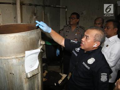 Petugas polisi dari Reskrimsus menunjukan drum tempat pembuatan ciu saat menggelar rilis di kawasan Pekojan, Tambora, Jakarta (3/5). Dari industri rumahan tersebut polisi menyita 22.000 liter bahan baku fermentasi ciu. (Liputan6.com/Arya Manggala)
