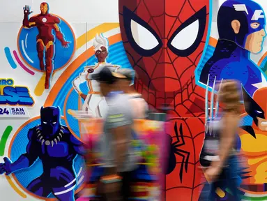 Para peserta konvensi melintasi dinding bergambar karakter superhero Marvel saat malam pratinjau Comic-Con International, Rabu, 24 Juli 2024, di San Diego. (AP Photo/Chris Pizzello)