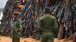 Petugas keamanan berjaga di depan senjata ilegal yang akan dibakar di Kajiado County, Kenya (15/11). Selain itu juga, tingkat perampokan yang menggunakan senjata makin tinggi dan mengganggu keamanan Kenya. (AFP/Tony Karumba)