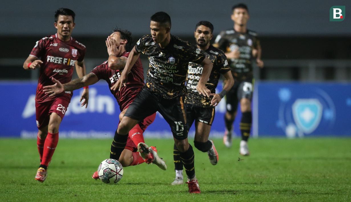 Pemain Persis Solo, Irfan Bachdim (tengah) terjatuh usai gagal melewati pemain Rans Cilegon FC, Muhammad Fadila Akbar dalam laga final Liga 2 2021 di Stadion Pakansari, Bogor, Kamis (30/12/2021). (Bola.com/Bagaskara Lazuardi)