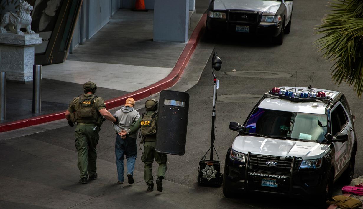 Aparat kepolisian mengamankan pelaku penembakan di Las Vegas Boulevard, Las Vegas, Sabtu (25/3). Polisi terlibat negosiasi sengit berjam-jam, sebelum akhirnya pelaku menyerahkan diri tanpa melibatkan kontak senjata. (L.E. Baskow/Las Vegas Sun via AP)