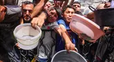 Warga Palestina berdesakan berebut makanan yang sudah dimasak dari dapur umum di Jabalia, Jalur Gaza Utara, pada 17 Mei 2025. (Bashar TALEB/AFP)
