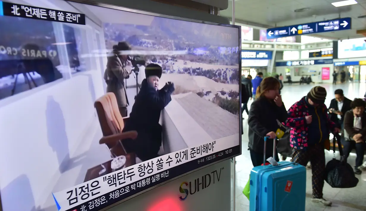Warga melewati layar TV yang menyiarkan berita tentang pemimpin Korut, Kim Jong-Un di stasiun kereta di Seoul, Korsel, Jumat (4/3). Kim Jong-Un memerintahkan pasukannya menyiagakan senjata nuklir untuk bisa digunakan kapan saja. (AFP PHOTO/Jung YEON-JE)