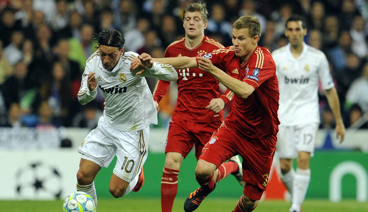 Gelandang Real Madrid, Mesut Oezil (kiri) menguasai bola dibayangi bek Bayern Munchen, Holger Badstuber pada laga leg kedua semifinal Liga Champions 2011/2012 di Santiago Bernabeu Stadium, Madrid (25/4/2012). Mesut Oezil tercatat membuat 4 gol dan 3 assist ke gawang Bayern Munchen dari total 17 pertemuan saat berseragam Schalke, Werder Bremen, Real Madrid dan Arsenal sejak muism 2006/2007 hingga 2016/2017. Hanya bersama Schalke ia gagal menyumbang gol maupun assist. (AFP/Dani Pozo)