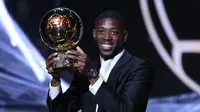 Penyerang Paris Saint-Germain (PSG), Ousmane Dembele, mengangkat trofi Ballon d'Or 2025 yang diraihnya di Theatre du Chatelet, Paris, Selasa (23/9/2025) dini hari WIB. (Franck FIFE / AFP)