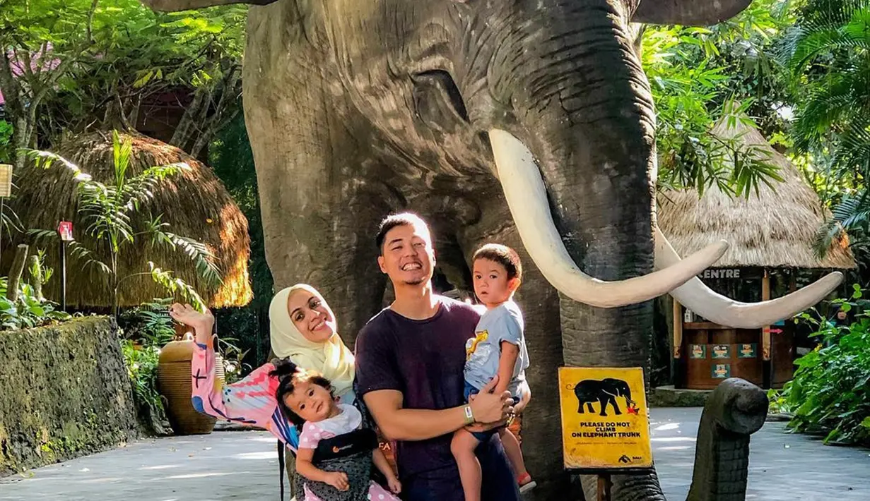 <p>Ini momen keluarga kecil Nycta Gina saat berlibur ke Taman Safari di Bali. Walaupun tak bisa foto bareng dengan gajah asli, keluarga ini tetap senang dan ceria foto dengan patung gajah. (Sumber: Liputan6.com/IG/@missnyctagina)</p>