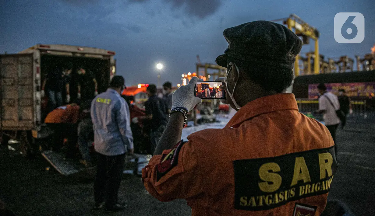 Petugas memotret proses pemindahan serpihan Sriwijaya Air SJ 182 di Terminal JICT 2, Tanjung Priok, Jakarta, Kamis (21/1/2020).  Serpihan Sriwijaya Air SJ 182 dipindahkan dari Terminal JICT 2 ke kantor KNKT untuk dilakukan pemeriksaan dan identifikasi. (Liputan6.com/Faizal Fanani)