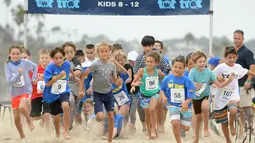 Sejumlah anak-anak berlari di atas pasir mengikuti 'Tot Trot' selama Nautica Malibu Triathlon di Pantai Zuma di Malibu, California (14/9). (Noel Vasquez / Getty Images untuk Nautica / AFP)