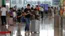 Calon penumpang mendorong koper ketika menunggu jadwal penerbangan di aula keberangkatan bandara di Hong Kong, Rabu (14/8/2019). Bandara Hong Kong kembali membuka penerbangan keberangkatan pada Rabu pagi setelah sempat lumpuh selama dua hari terakhir akibat demonstrasi. (AP/Vincent Thian)