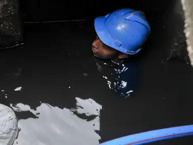Petugas harian lepas (PHL) Sudin SDA membersihkan endapan pasir dan sampah dalam gorong-gorong di Jalan Gatot Subroto, Jakarta, Jumat (10/3). Pembersihan dilakukan karena di kawasan ini banjir selalu datang saat hujan turun. (Liputan6.com/Yoppy Renato)