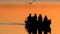 Nelayan lokal mengayuh perahu saat matahari terbenam di danau Lusiai dekat kota kecil Ignalina, sekitar 120 km (74,5 mil) utara ibukota Vilnius, Lithuania (3/6/2019). (AP Photo/Mindaugas Kulbis)