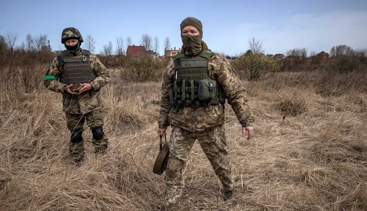 Anggota regu penjinak bom berjalan di ladang ranjau dekat Brovary, timur laut Kiev, di tengah invasi militer Rusia pada 14 April 202. Rusia sudah menarik tentara mereka dari Kiev dan mengalihkan sebagian besar fokus perangnya ke wilayah Ukraina timur pada akhir Maret. (FADEL SENNA/AFP)