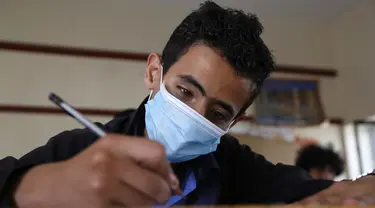 Seorang siswa yang mengenakan masker mengikuti ujian di sebuah sekolah di Sanaa, Yaman (30/8/2020). (Xinhua/Mohammed Mohammed)
